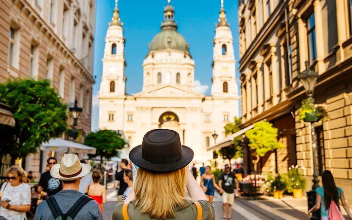 Tourists walking towards St. Stephen's Basilica in Budapest during a guided bus tour.