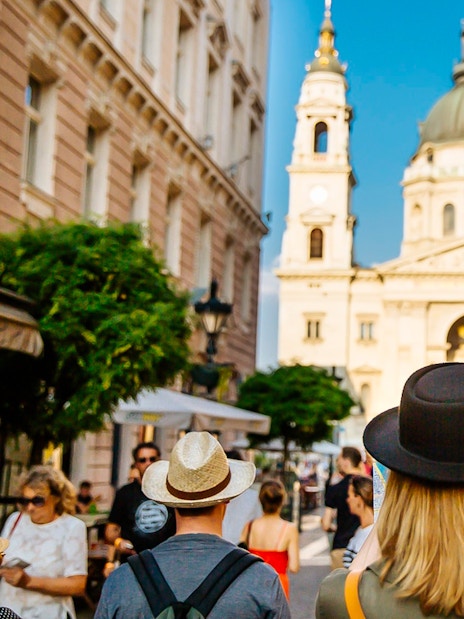 Tourists walking towards St. Stephen's Basilica in Budapest during a guided bus tour.