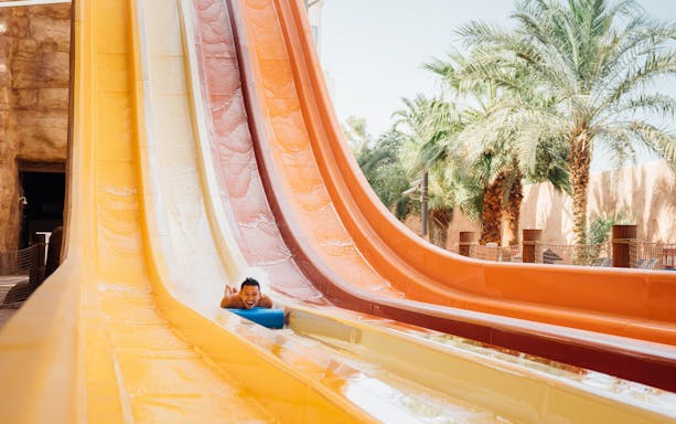Person sliding down colorful water slide at Ehsan Waterpark.