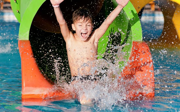 Child splashing out of a colorful water slide at Ehsan Waterpark.