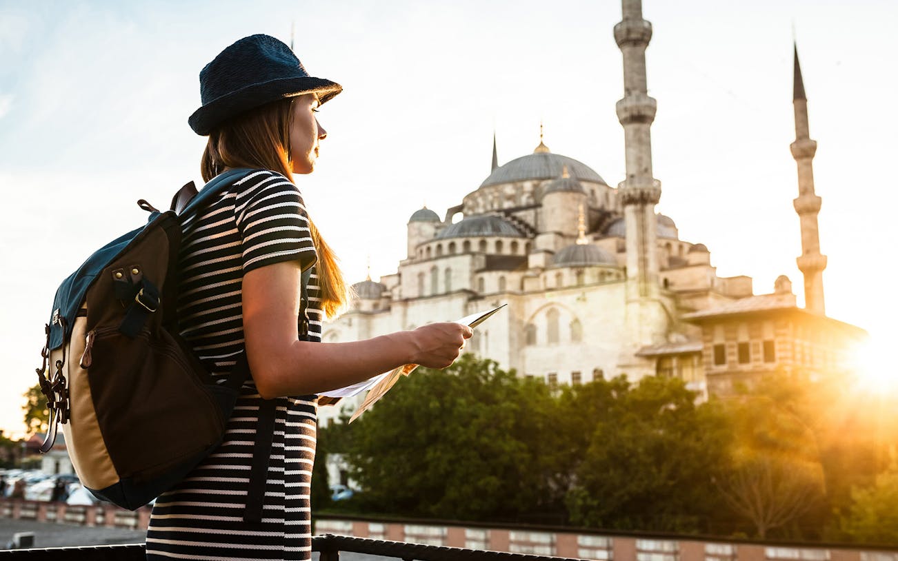 Traveler with a map near the Blue Mosque in Istanbul during a guided tour.