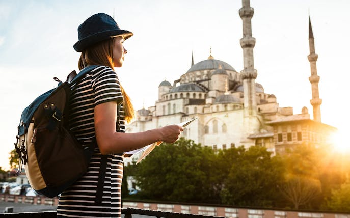 Traveler with a map near the Blue Mosque in Istanbul during a guided tour.