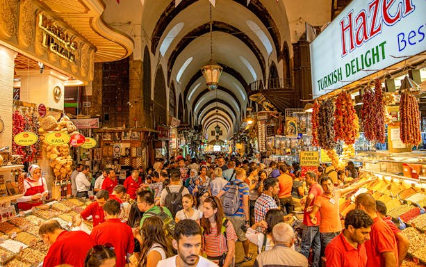 Crowded aisle in Istanbul's Grand Bazaar with spice and souvenir stalls.