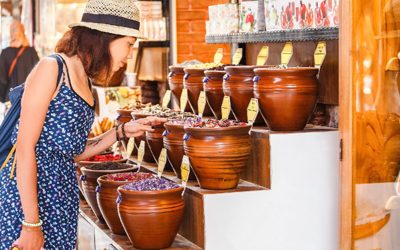 Woman examining spice jars at Grand Bazaar walking tour.