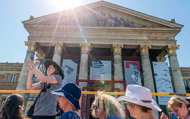 Visitors on a hop-on hop-off bus tour in front of the Hungarian National Museum, Budapest.
