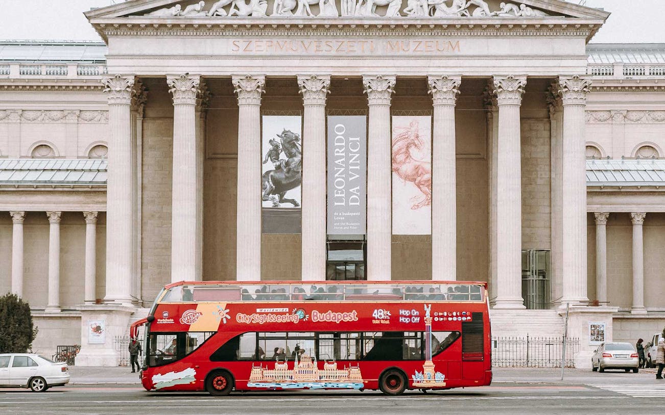 Red hop-on hop-off tour bus in front of Budapest's Szépművészeti Múzeum.