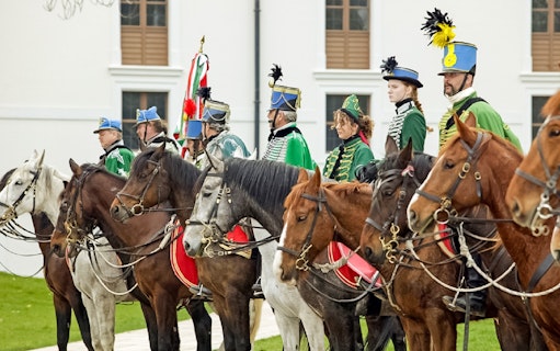 Hungarian hussars on horseback in traditional attire at Gödöllő Palace, Budapest.