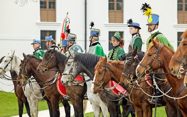 Hungarian hussars on horseback in traditional attire at Gödöllő Palace, Budapest.