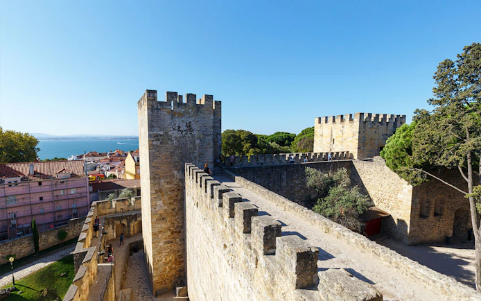 Surrounding wall of St. George’s Castle in Lisbon with city and sea view.