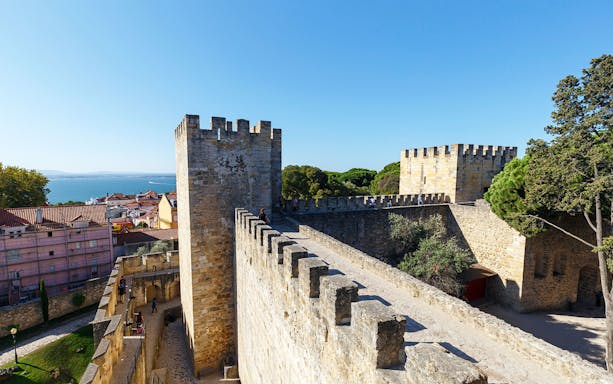 Surrounding wall of St. George’s Castle in Lisbon with city and sea view.