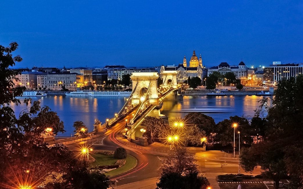 Chain Bridge and St. Stephen's Basilica illuminated at night in Budapest.