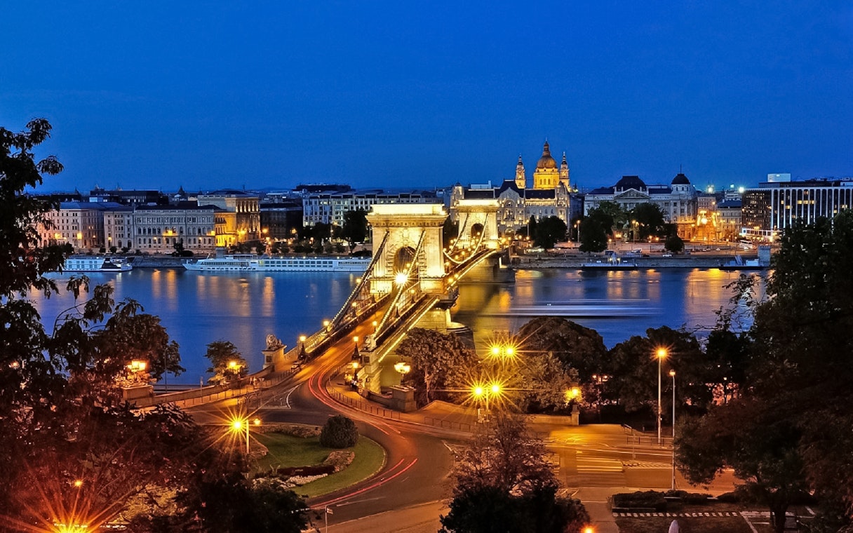 Chain Bridge and St. Stephen's Basilica illuminated at night in Budapest.