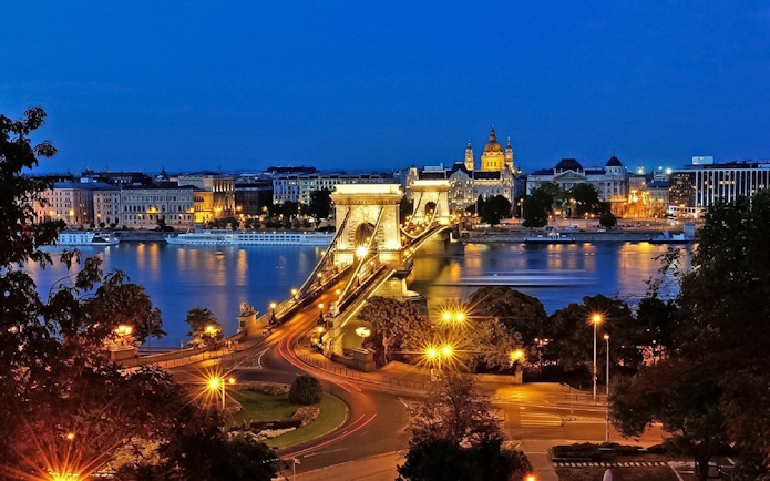 Chain Bridge and St. Stephen's Basilica illuminated at night in Budapest.