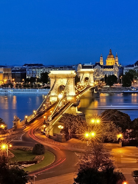 Chain Bridge and St. Stephen's Basilica illuminated at night in Budapest.