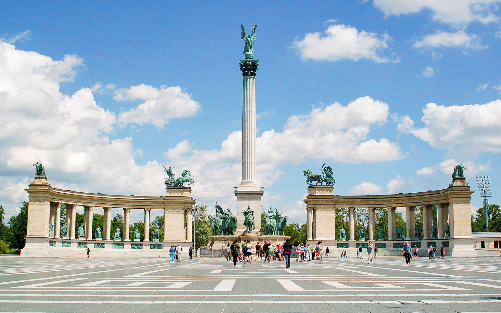 Heroes' Square in Budapest with tourists exploring the iconic statues and column.