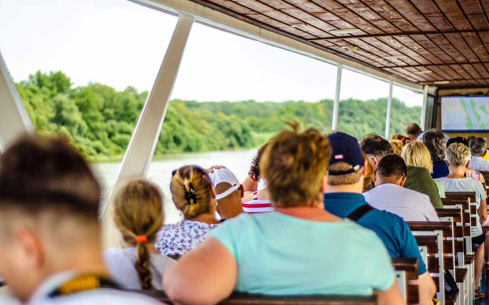 Tourists seated on a boat cruising the Danube River during a full-day tour from Budapest.