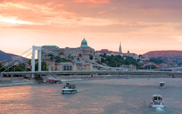 Danube River cruise with view of Buda Castle and Elizabeth Bridge in Budapest at sunset.