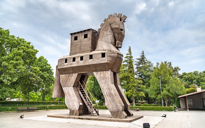 Wooden Trojan Horse replica at Ancient Troy, Turkey, surrounded by trees.