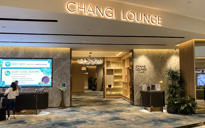 Entrance to Changi Lounge at Singapore Airport with reception desk and signage.