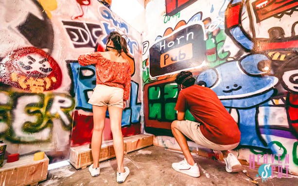 Visitors painting graffiti at Heaven Spot Graffiti Warehouse, Singapore.