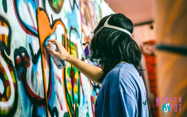 Graffiti artist spray painting at Heaven Spot Graffiti Warehouse, Singapore.