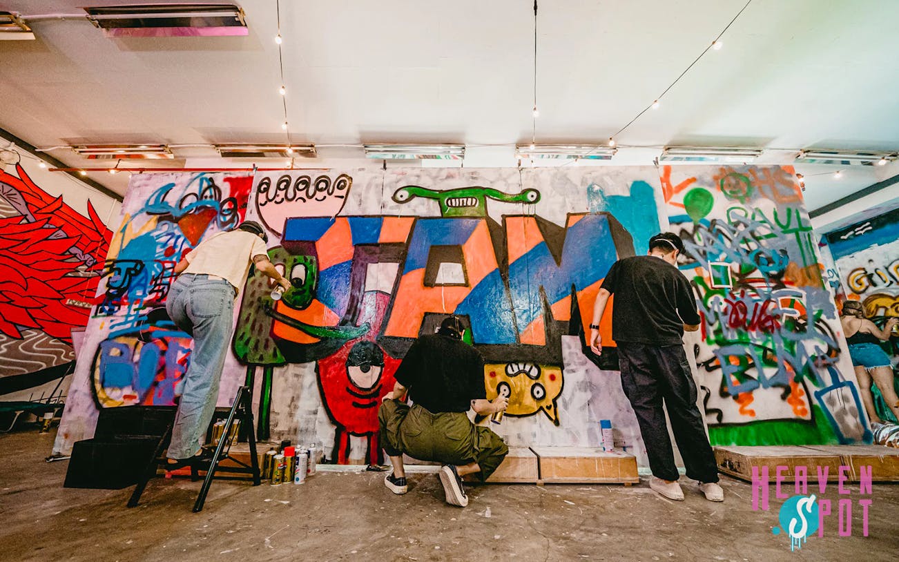 Artists creating colorful graffiti at Heaven Spot Graffiti Warehouse, Singapore.