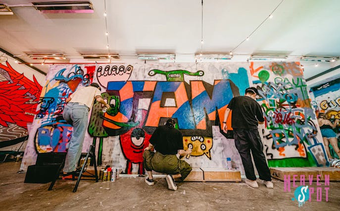 Artists creating colorful graffiti at Heaven Spot Graffiti Warehouse, Singapore.