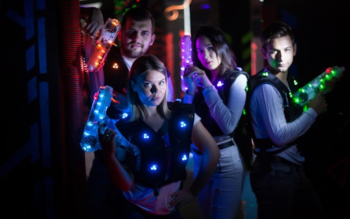 Group playing laser tag at Laser Quest Bukit Batok with glowing vests and blasters.