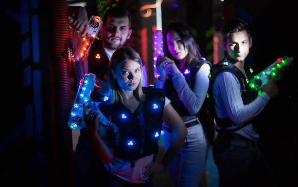 Group playing laser tag at Laser Quest Bukit Batok with glowing vests and blasters.