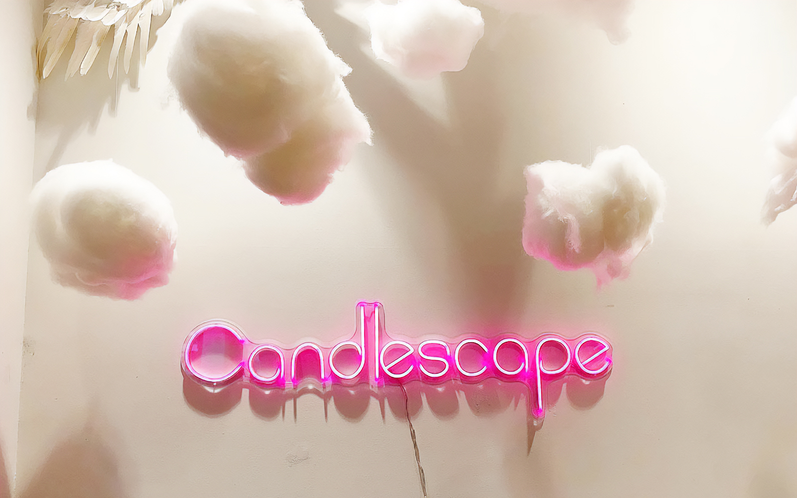 Candlescape neon sign with decorative clouds above.