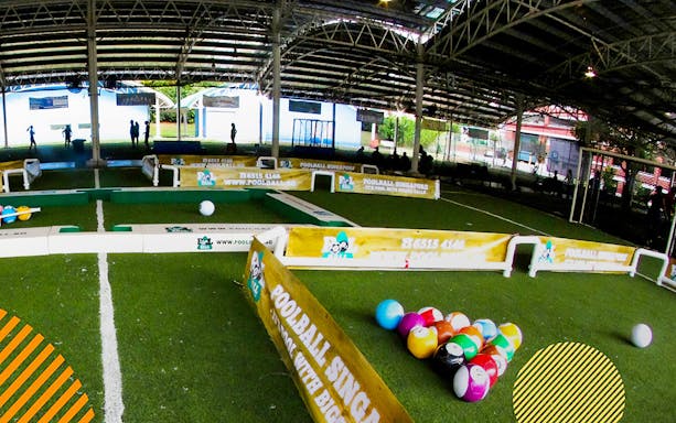 Indoor poolball arena at FunEmpire Singapore with colorful soccer balls on green turf.