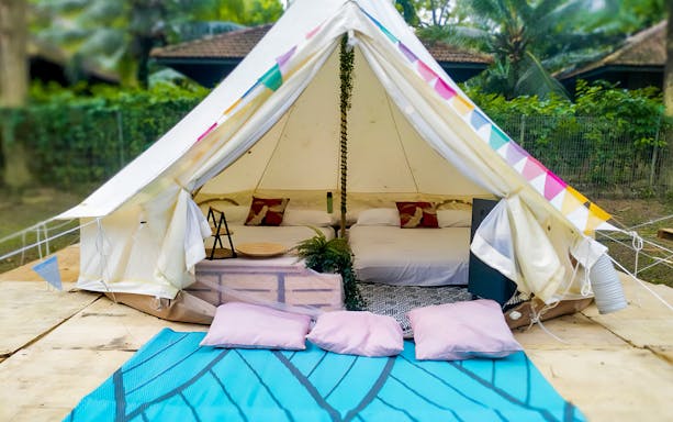 Glamping tent with cozy beds and colorful decor at a forest retreat.