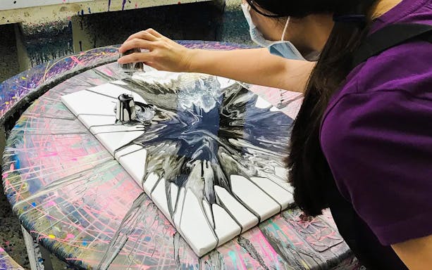 Person creating spin art at Spin Paint House with black and white paint.