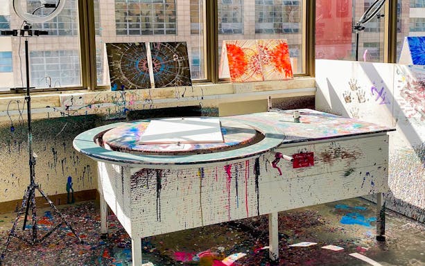 Spin Paint House studio with colorful splattered paint and artwork on display.