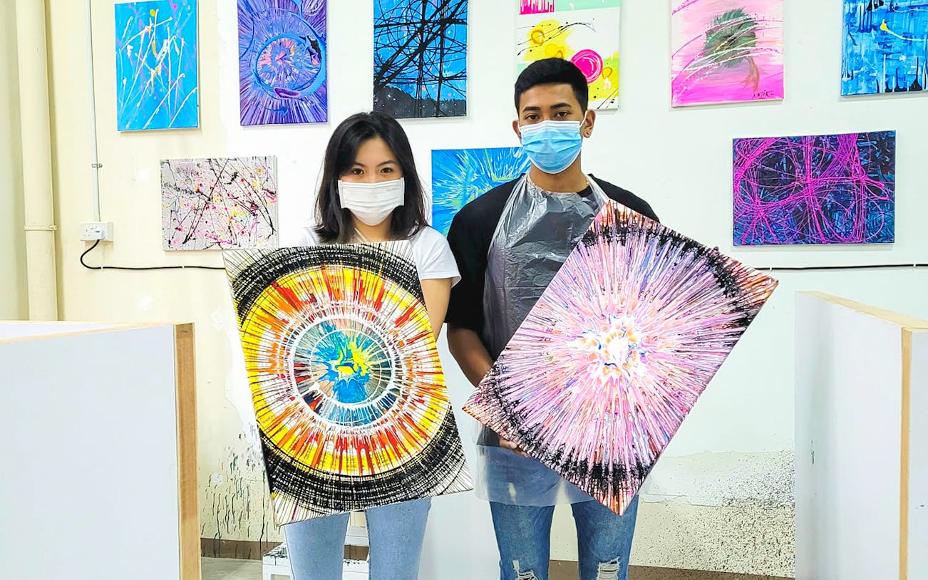 Visitors holding spin art paintings at Spin Paint House.