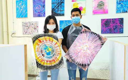 Visitors holding spin art paintings at Spin Paint House.