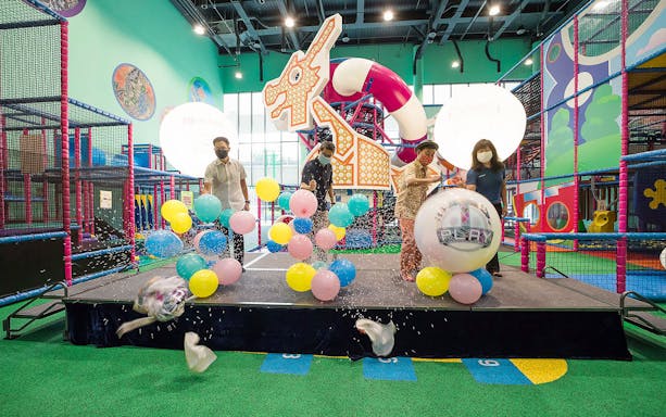 People popping balloons at T-Play Bukit Batok indoor playground event.