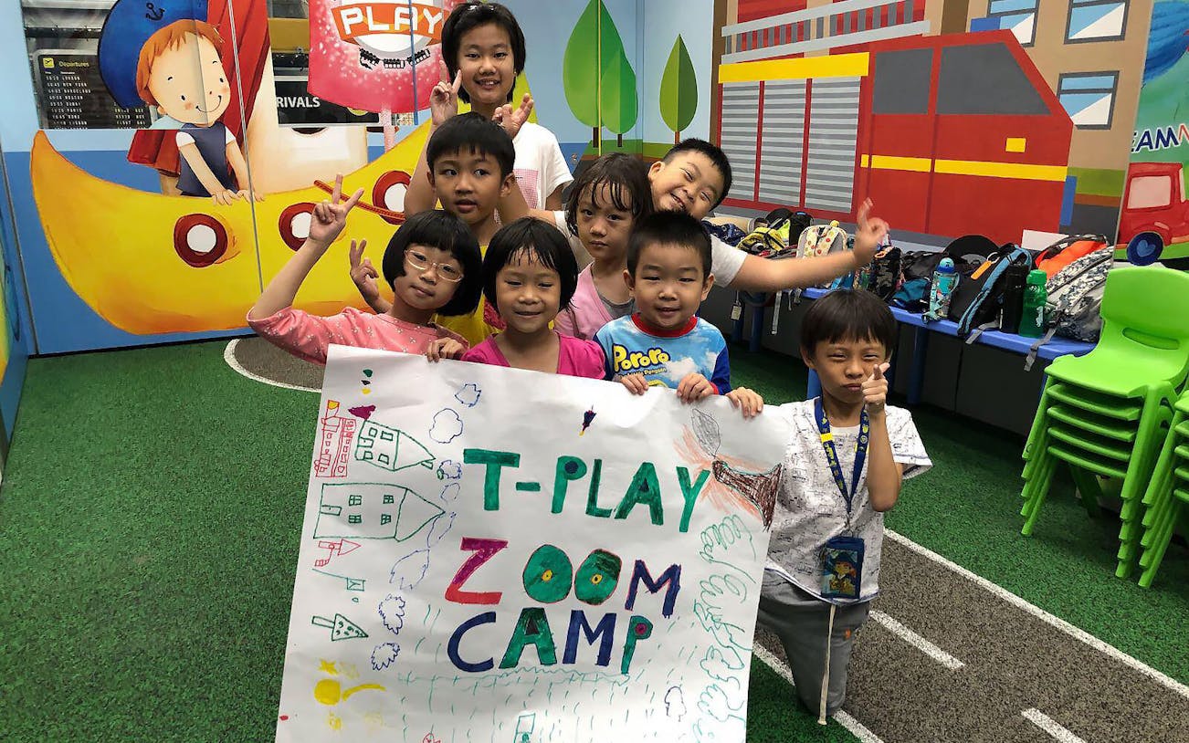 Children holding a T-Play Zoom Camp sign at T-Play Bukit Batok indoor playground.