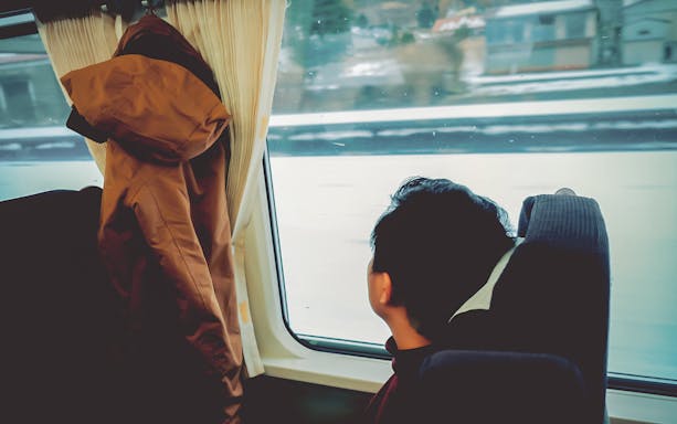 Passenger gazing out train window on Hokkaido Sapporo-Furano route.
