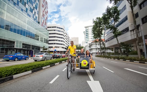 Trishaw ride through Singapore city streets with passengers enjoying the view.