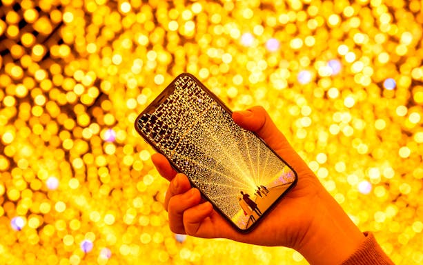 Hand holding a phone displaying Nabana no Sato illuminations, Nagoya tour.