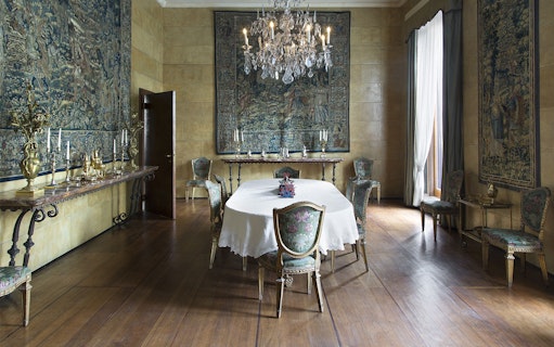 Villa Necchi Campiglio dining room with ornate chairs, chandelier, and tapestries.