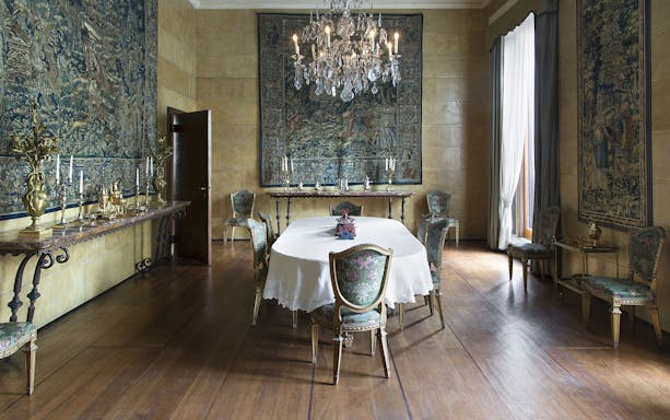 Villa Necchi Campiglio dining room with ornate chairs, chandelier, and tapestries.