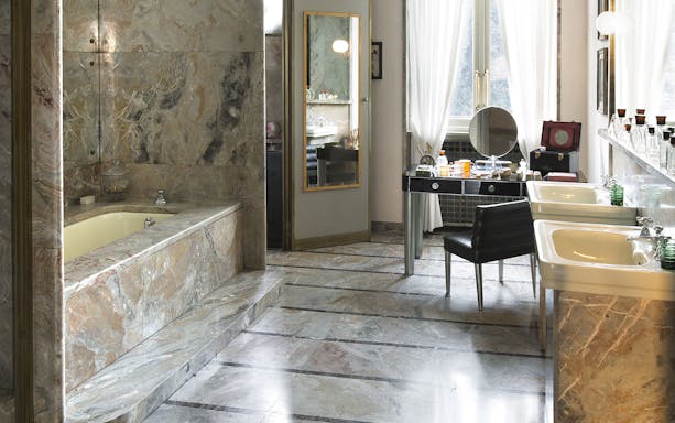 Luxurious marble bathroom at Villa Necchi Campiglio, featuring a vintage vanity and dual sinks.