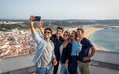 Group taking selfie with Nazaré beach view on Porto, Nazaré & Óbidos tour from Lisbon.