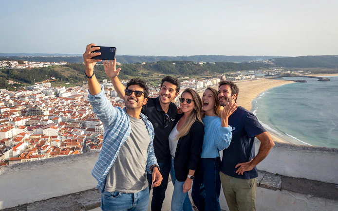 Group taking selfie with Nazaré beach view on Porto, Nazaré & Óbidos tour from Lisbon.