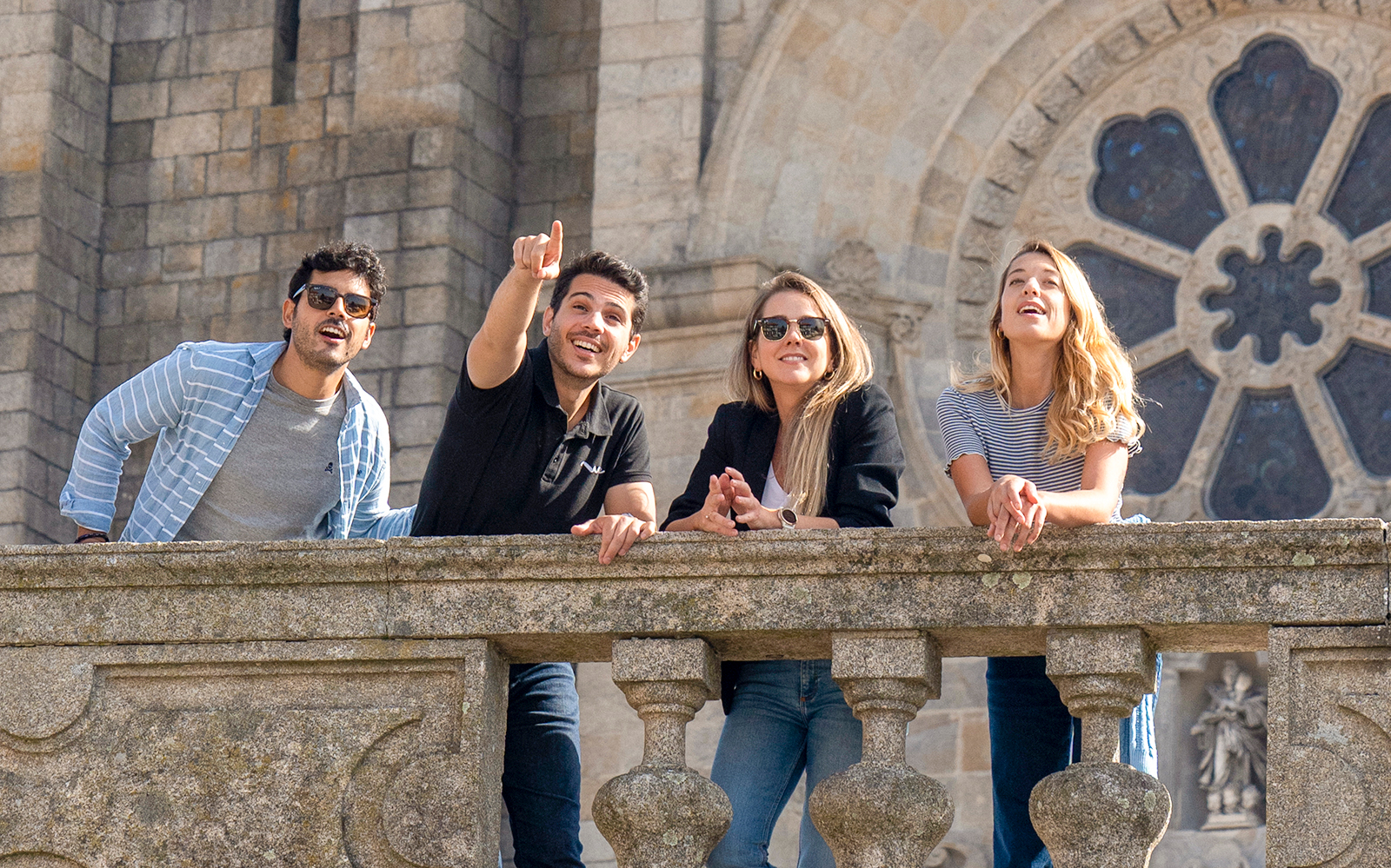 Group of tourists enjoying a view from a historic stone balcony in Porto.