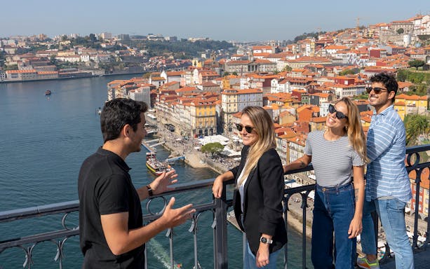 Tour group enjoying a scenic view of Porto's historic Ribeira district from a riverside vantage point.