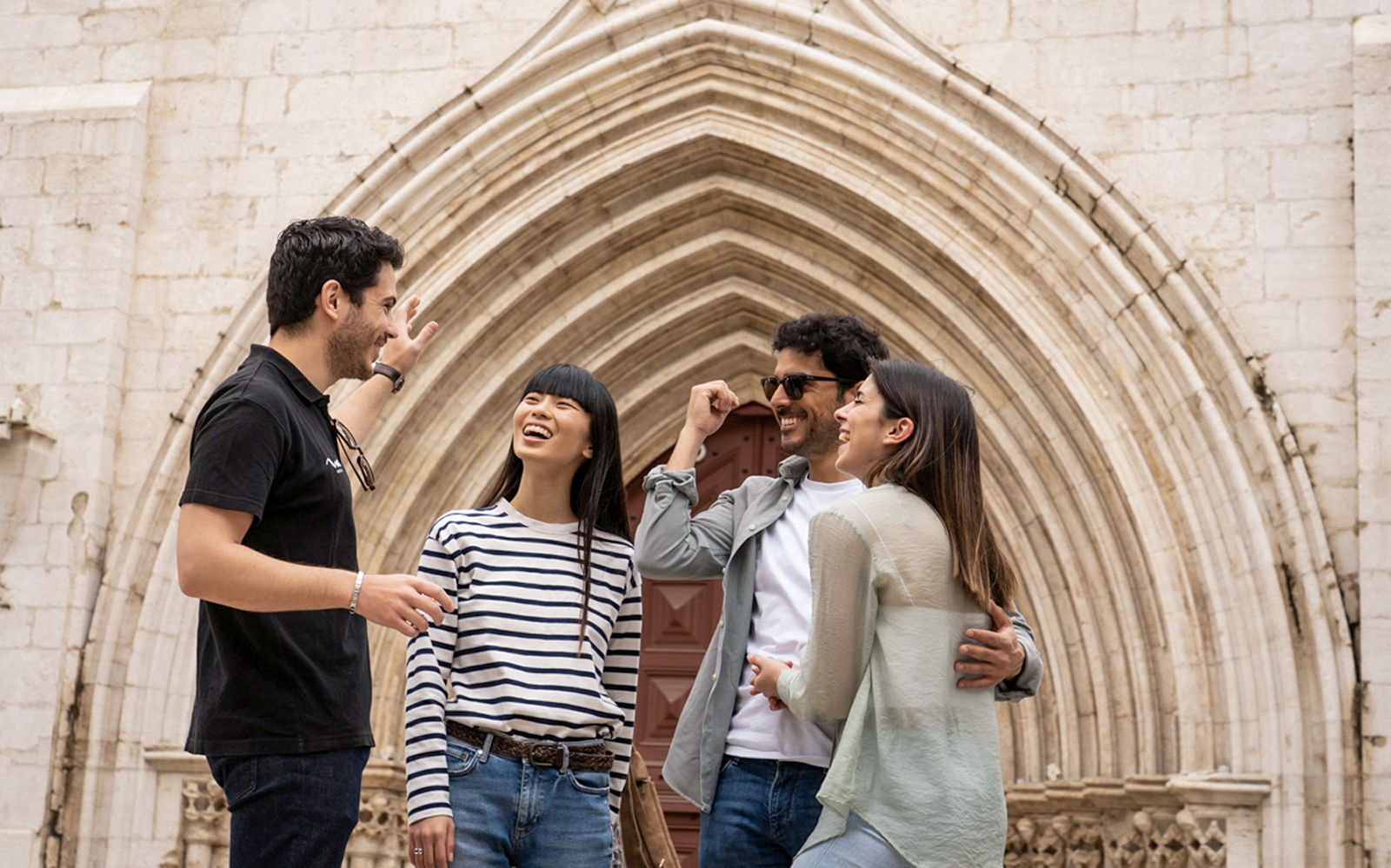 Group enjoying Lisbon Old Town tour in front of historic archway.