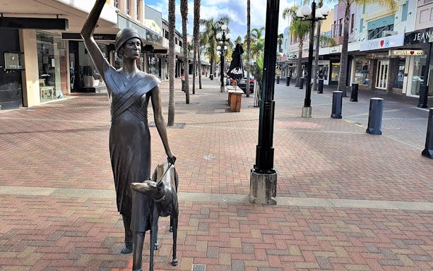 Statue of a woman with a dog on a street in Napier, New Zealand.